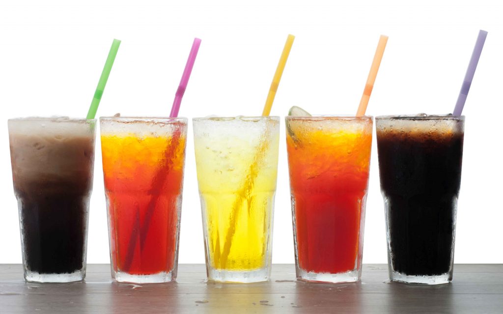 Four glasses of cold, fresh, homemade sodas with ice and straws